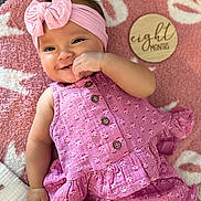 Ally joined the competition — help win amazing prizes! baby, infant, smile, pink, headband, bow, blanket, clothing, pattern, button, hand, face, cute, portrait, lying_down, milestone, wooden_plaque, soft_texture, happy, child