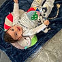 baby, child, toy, blanket, plush_toy, ball, floor, slipper, smiling, clothing, pillow, indoor, cute, infant, happy, socks, person, head, face, lying_down