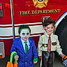 Kamrynn is registered to the contest to win money with this photo: child, costume, halloween, joker, sheriff, fire_truck, face_paint, smile, toy, bag, hat, tie, handcuffs, outdoor, street, fun, holiday, dress_up, green_hair, blue_suit