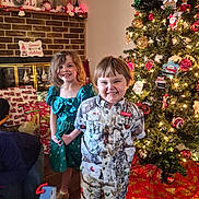 Kamrynn is registered to the contest to win money with this photo: child, christmas_tree, holiday, presents, smile, indoor, festive, decorations, fireplace, toy, girl, boy, clothing, home, celebration, lights, ornaments, floor, happy, family