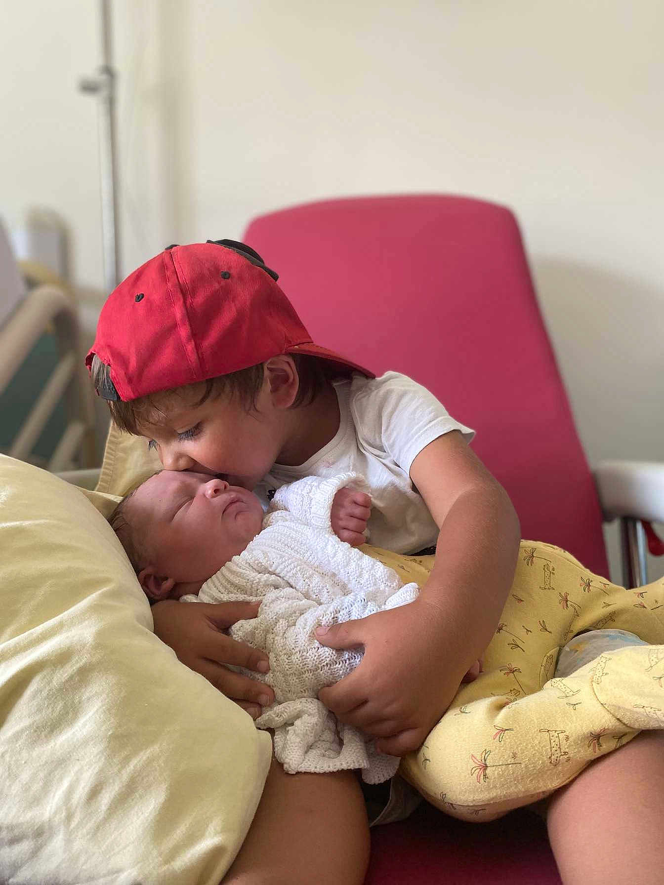 Diego Et Melyo a rejoint le concours — aidez-le/la à gagner de superbes lots ! child, newborn, baby, kiss, red_cap, white_shirt, blanket, pillow, chair, indoor, family, affection, love, cuddle, comfort, sleeping_baby, holding, toddler, portrait, soft_lighting