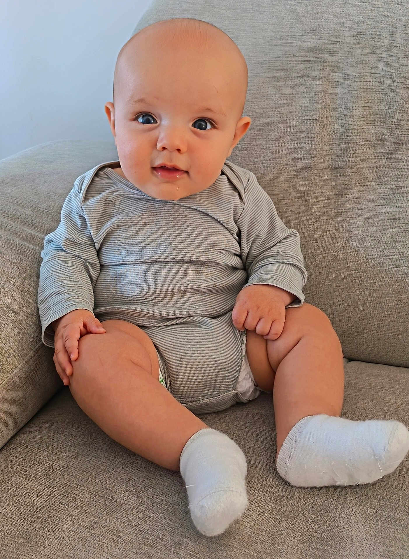 Idriss participe au concours pour gagner de l'argent avec cette photo : baby, infant, child, couch, socks, onesie, striped_clothing, drool, face, eyes, hands, legs, skin, seated, indoors, comfortable, cute, soft_furniture, portrait, smiling