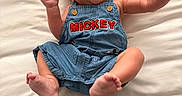 Rowan is registered to the contest to win money with this photo: baby, barefoot, child, clothing, cute, denim, expression, feet, happy, indoors, infant, joy, mickey, overalls, portrait, pose, raised_hands, smiling, soft_surface, white_background