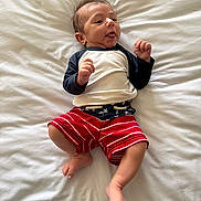 Rowan joined the competition — help win amazing prizes! baby, bed, child, clothing, cute, expression, feet, hair, hands, indoors, infant, long_sleeve_shirt, lying_down, person, portrait, shorts, skin, smiling, tongue_out, white_sheet