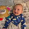 baby, bed, blanket, blue_onesie, child, cloud_pattern, comfort, cozy, cushion, cute, elephant_pattern, face, happy, indoor, infant, person, plush_toy, sleepwear, smiling, soft_toy