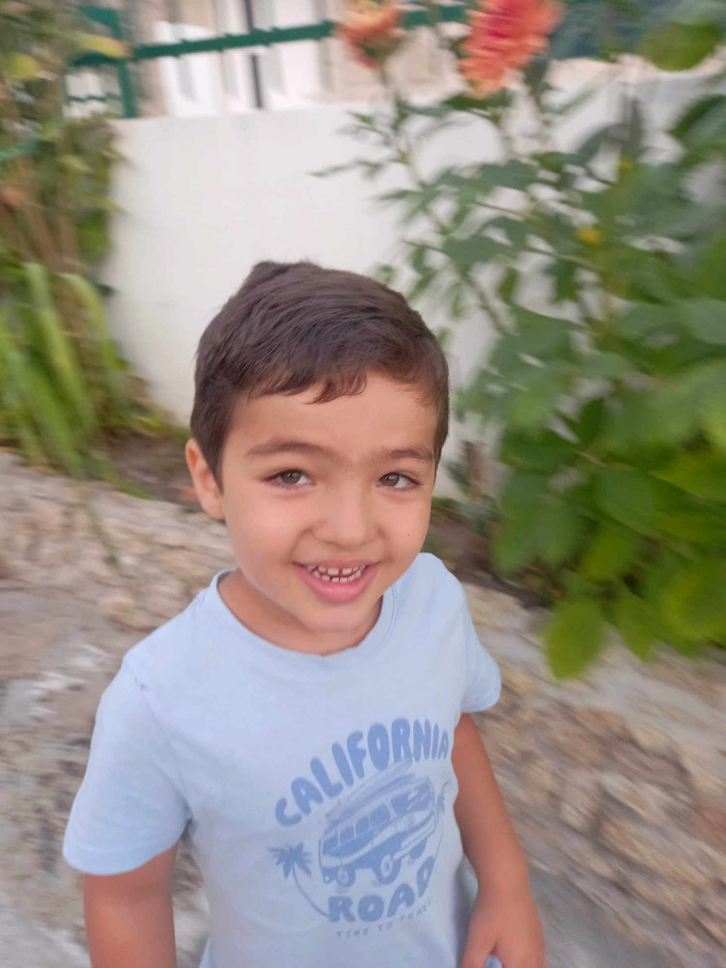 Lourenço a rejoint le concours — aidez-le/la à gagner de superbes lots ! child, boy, smiling, outdoor, tshirt, short_sleeve, greenery, white_fence, happy, casual, portrait, standing, young, person, nature, daylight, face, hair, road, california