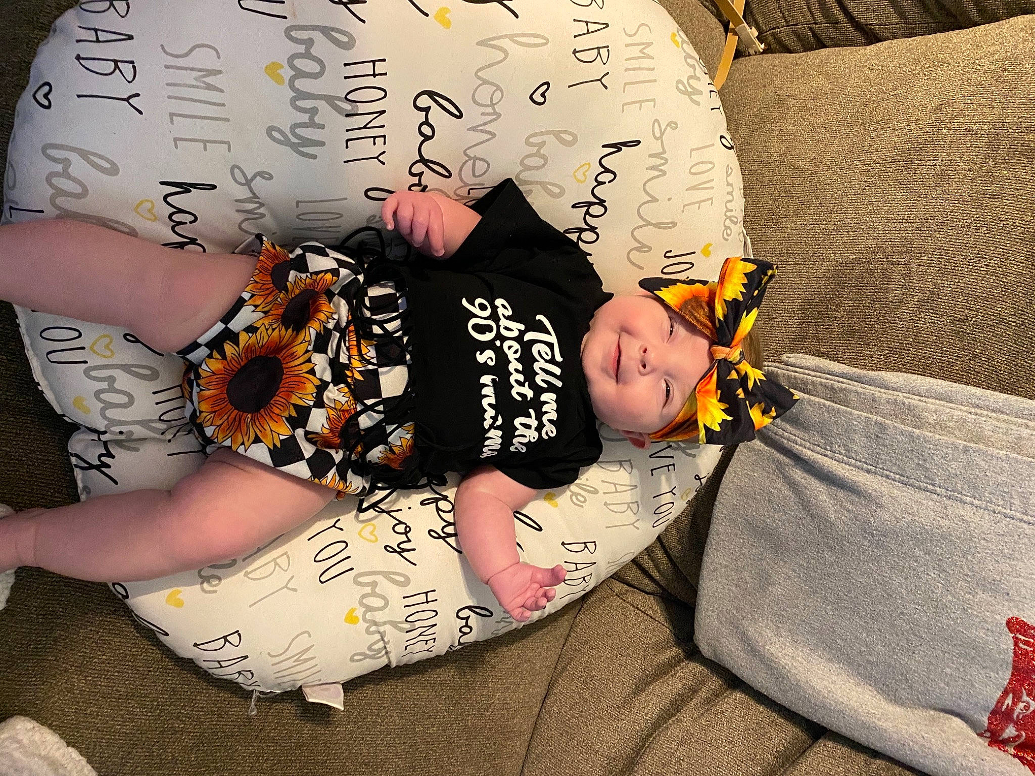 Hadley is registered to the contest to win money with this photo: baby, baby_sleeping, baby_toddler_clothing, child, comfort, flooring, font, happy, hat, headwear, human_body, knee, linens, orange, pattern, person, sitting, sleeve, sock, t_shirt