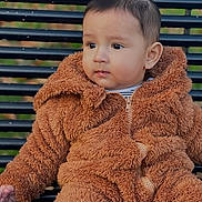 Daniyal joined the competition — help win amazing prizes! baby, brown_outfit, casual, child, curious, cute, daylight, expression, face, fur_clothing, innocent, outdoor, park_bench, person, portrait, seat, sitting, toddler, warm_clothing, young_child