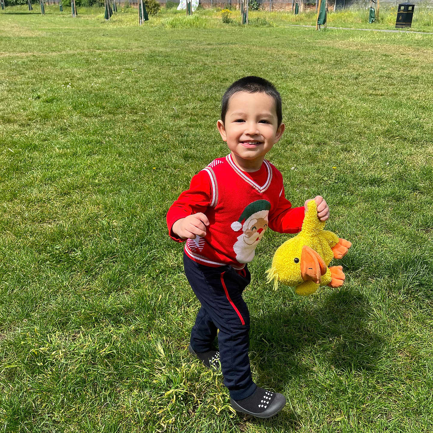 Daniyal joined the competition — help win amazing prizes! child, smiling, running, red_sweater, stuffed_toy, yellow_duck, grass, park, outdoor, daytime, happy, person, playing, toy, nature, casual_clothing, greenery, sunny, cute, young