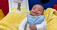 Destin joined the competition — help win amazing prizes! baby, smiling, yellow_blanket, blue_bib, blue_pants, play_structure, plastic, child, indoor, poem, text, cute, happy, infant, lying_down, colorful, soft_texture, portrait, young_child, educational