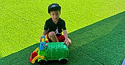 Domink joined the competition — help win amazing prizes! child, toy_truck, playground, slide, artificial_grass, cap, black_shirt, outdoor, daylight, playing, kids, recess, fun, colorful, green, red_slide, blue_slide, people, shadow, summer