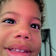 Domink is registered to the contest to win money with this photo: child, face, close_up, smile, eyes, teeth, indoor, curly_hair, skin, portrait, happy, young, person, nostrils, eyelashes, mouth, cheeks, baby_teeth, background, furniture