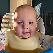 Anna a rejoint le concours — aidez-le/la à gagner de superbes lots ! baby, high_chair, bib, child, smiling, face, blue_eyes, indoor, sunlight, shadow, person, cute, infant, expression, clothing, feeding, front_view, young_child, happy, portrait