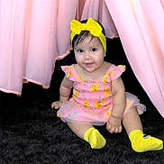 Maryfer joined the competition — help win amazing prizes! baby, child, infant, smiling, yellow_bow, yellow_socks, pink_dress, floral_pattern, curtains, black_carpet, sitting, cute, indoors, portrait, happy, young_child, headband, toddler, person, soft_lighting