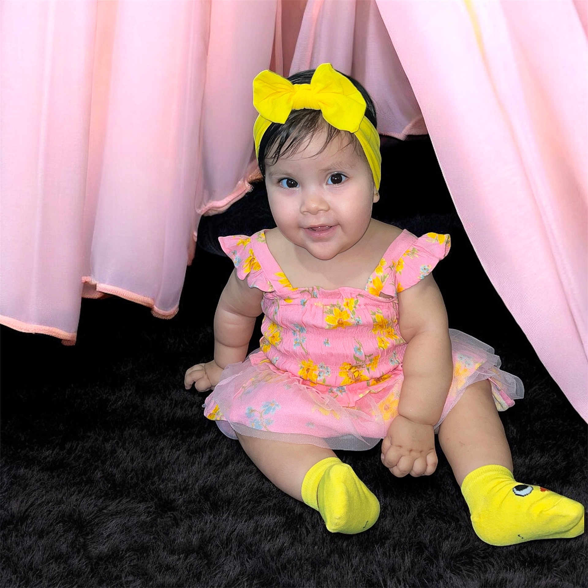 Maryfer joined the competition — help win amazing prizes! baby, child, infant, smiling, yellow_bow, yellow_socks, pink_dress, floral_pattern, curtains, black_carpet, sitting, cute, indoors, portrait, happy, young_child, headband, toddler, person, soft_lighting