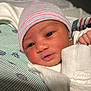 Riley is registered to the contest to win money with this photo: newborn, baby, infant, face, hat, blanket, clothing, sleepwear, portrait, closeup, skin, hand, cute, resting, indoors, soft, warm, striped, headwear, newborn_baby