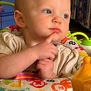 Zoey is registered to the contest to win money with this photo: baby, child, infant, face, blue_eyes, hand, finger, toy, colorful, play_area, animal_prints, clothing, indoor, expression, cute, portrait, closeup, thinking, seat, person