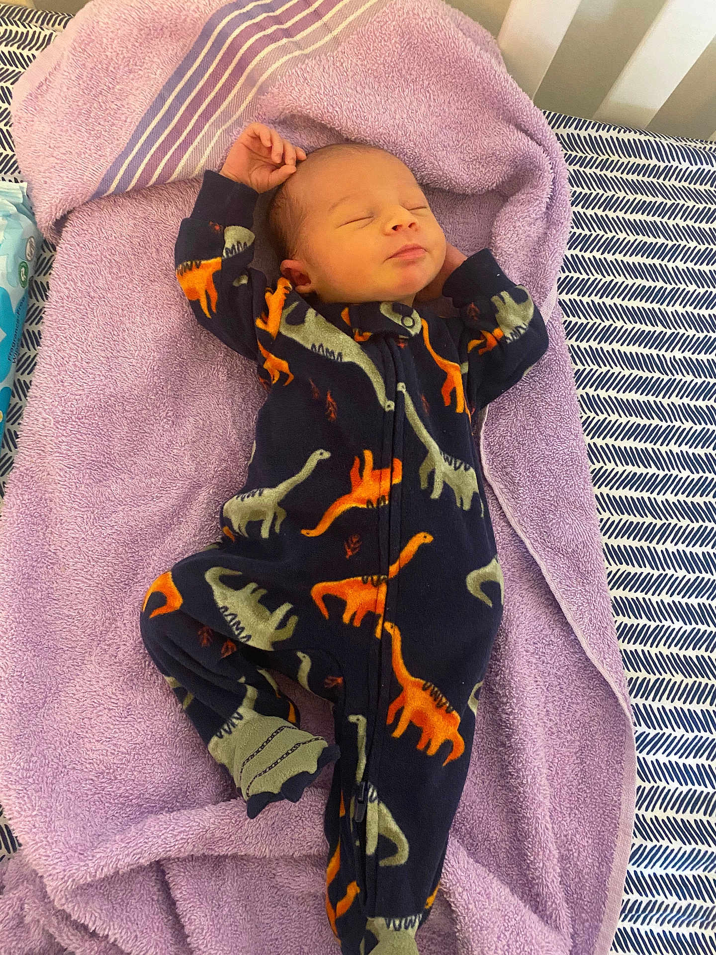Louis joined the competition — help win amazing prizes! baby, newborn, sleeping, onesie, dinosaur, purple_towel, bed, blanket, infant, child, cute, cozy, resting, soft, comfortable, clothing, pattern, footed_pajamas, indoors, portrait