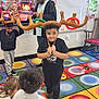 children, classroom, reindeer_antlers, holiday, christmas, inflatable_toys, carpet, child, boy, girl, adult, decorations, television, fireplace, festive, playful, indoor, furniture, rocking_chair, smiling