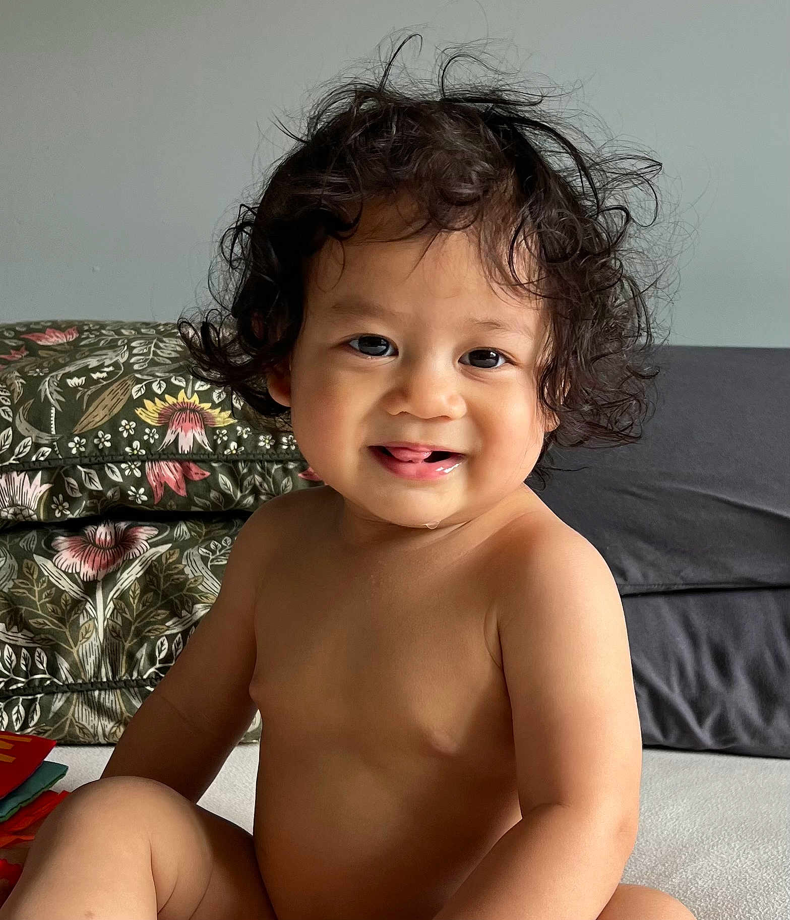 Jedidiah joined the competition — help win amazing prizes! toddler, child, curly_hair, smile, tongue, indoor, cushion, pattern, bare_chest, skin, face, eyes, nose, mouth, person, baby, sitting, cute, happy, young_child