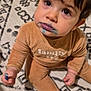 child, toddler, baby, face, eyes, marker, blue_marker, marker_smear, mouth, stain, onesie, clothing, hair, patterned_rug, carpet, sitting, indoor, hand, expression, portrait
