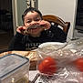 child, boy, smiling, eating, rib, food, plate, table, tomatoes, spoon, fork, plastic_container, plastic_bag, chair, dining_room, indoor, happy, face, meal, kitchen