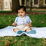 Dilan is registered to the contest to win money with this photo: toddler, child, baby, grass, blanket, outdoor, smiling, cute, happy, shirt, shorts, suspenders, shoes, tree, building, nature, portrait, sitting, daytime, playful