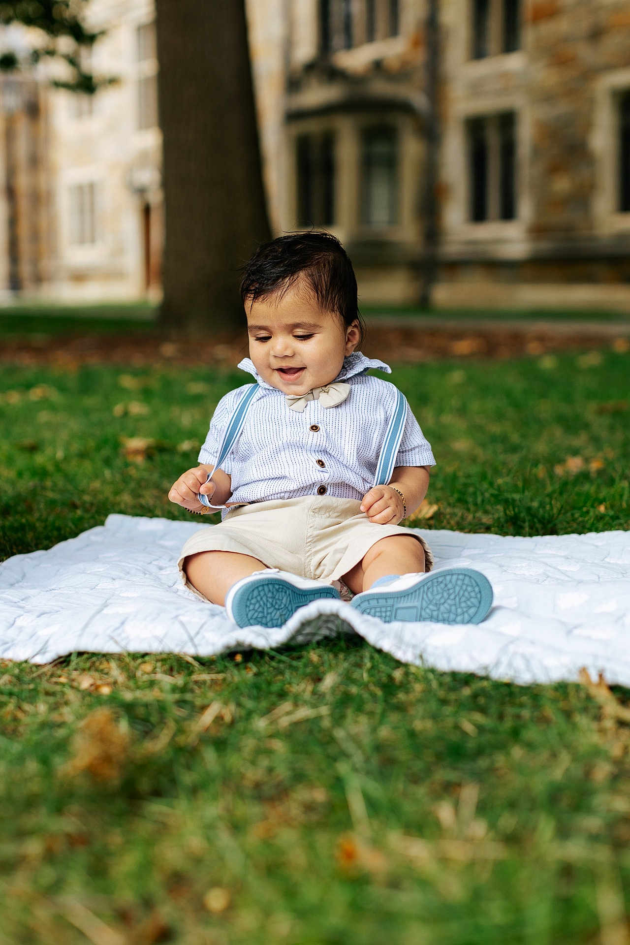 Dilan is registered to the contest to win money with this photo: toddler, child, baby, grass, blanket, outdoor, smiling, cute, happy, shirt, shorts, suspenders, shoes, tree, building, nature, portrait, sitting, daytime, playful