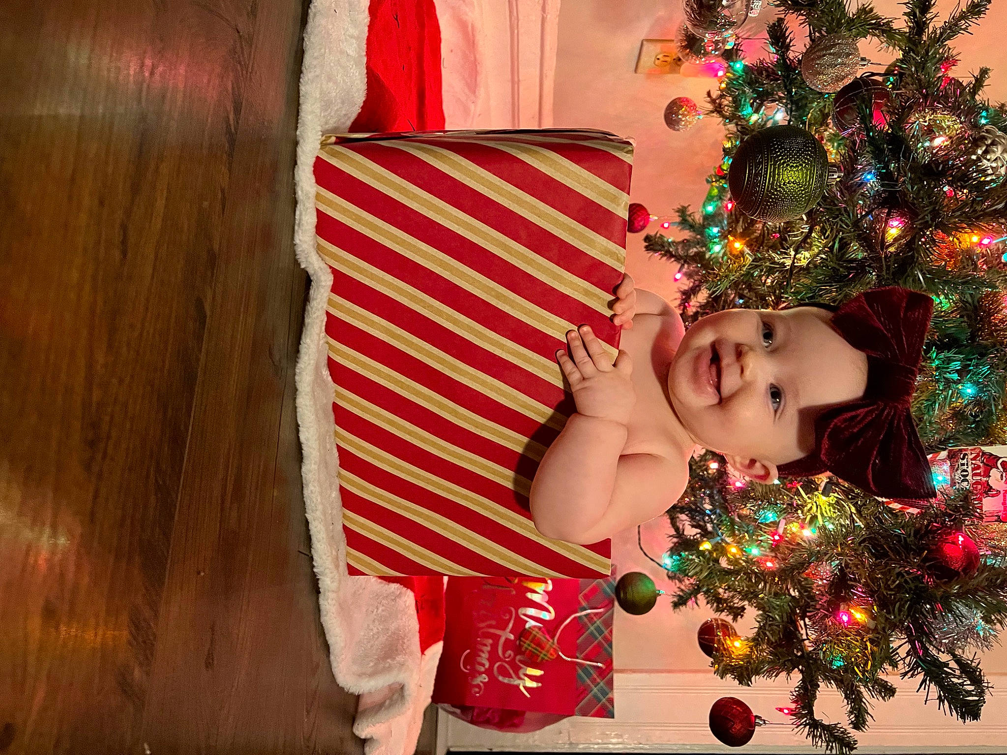 Kinsley is registered to the contest to win money with this photo: carmine, christmas, christmas_decoration, christmas_eve, christmas_ornament, christmas_tree, curtain, decoration, event, happy, headwear, holiday, holiday_ornament, interior_design, joy, ornament, pattern, person, room, sitting