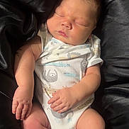 Messiah is registered to the contest to win money with this photo: baby, sleeping, onesie, infant, black_socks, satin, black_fabric, peaceful, cute, newborn, child, soft_lighting, portrait, resting, small_hands, small_feet, indoors, cozy, closeup, relaxed