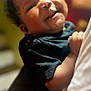 Milani is registered to the contest to win money with this photo: baby, child, smiling, curly_hair, black_clothing, indoor, portrait, happy, infant, cute, person, face, closeup, head, skin, hand, warm_lighting, blurred_background, holding, toddler