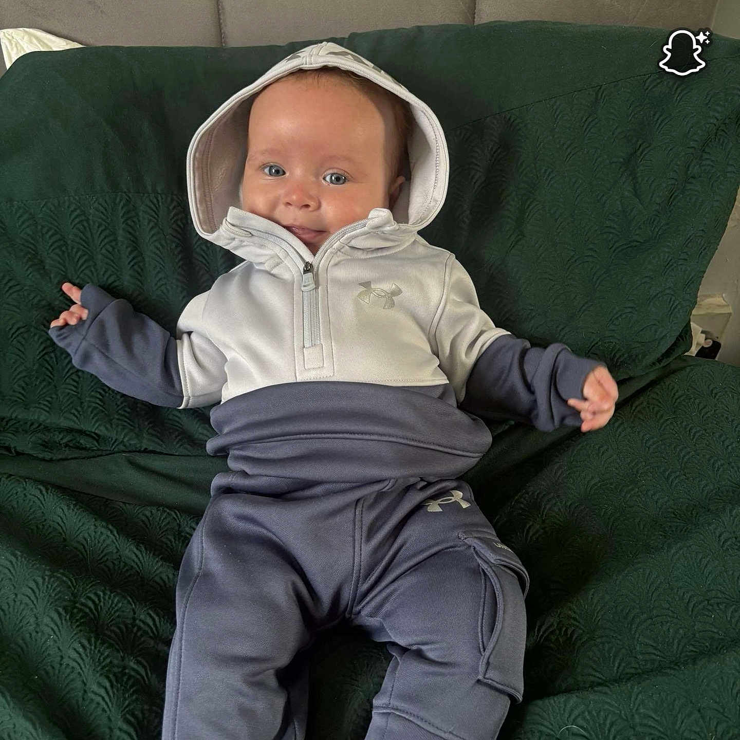 Roman-Lee joined the competition — help win amazing prizes! apparel, baby, child, clothing, comfortable, couch, cute, face, foot, green_couch, head, hoodie, indoor, infant, pants, person, relaxed, sitting, smiling, texture