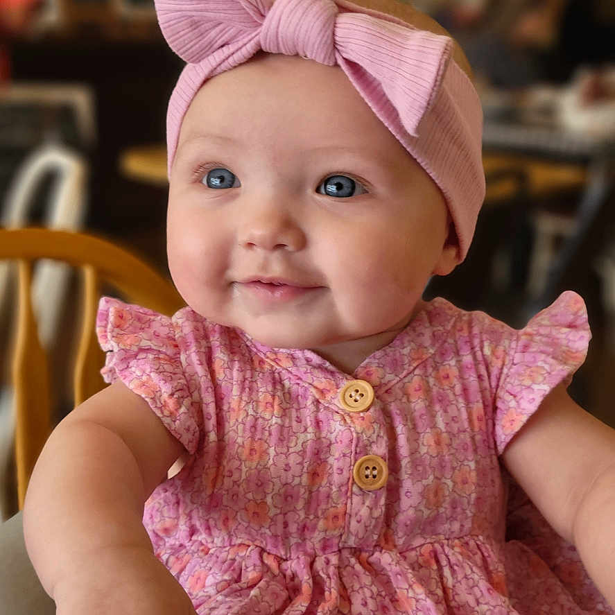 Hadley joined the competition — help win amazing prizes! baby, girl, child, headband, pink, dress, smile, blue_eyes, indoor, blurred_background, cute, happy, seated, wooden_chair, portrait, infant, clothing, fashion, person, toddler