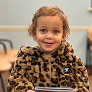 Bella is registered to the contest to win money with this photo: baby, bodypart, clothing, coat, face, finger, hand, happy, head, jacket, knitwear, longsleeve, person, photography, portrait, reading, sleeve, smile, sweater, text