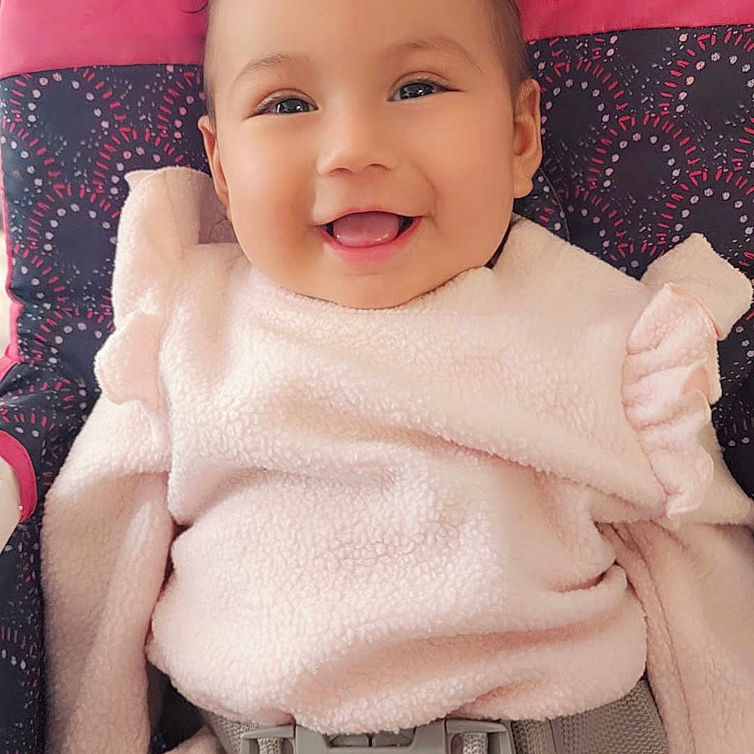 Avery Mae Zuniga is registered to the contest to win money with this photo: adorable, baby, bows, car_seat, child, child_seat, closeup, cute, face, happy, indoors, infant, pigtails, pink_clothing, portrait, safety_belt, smiling, soft_texture, warm_clothing, young_child