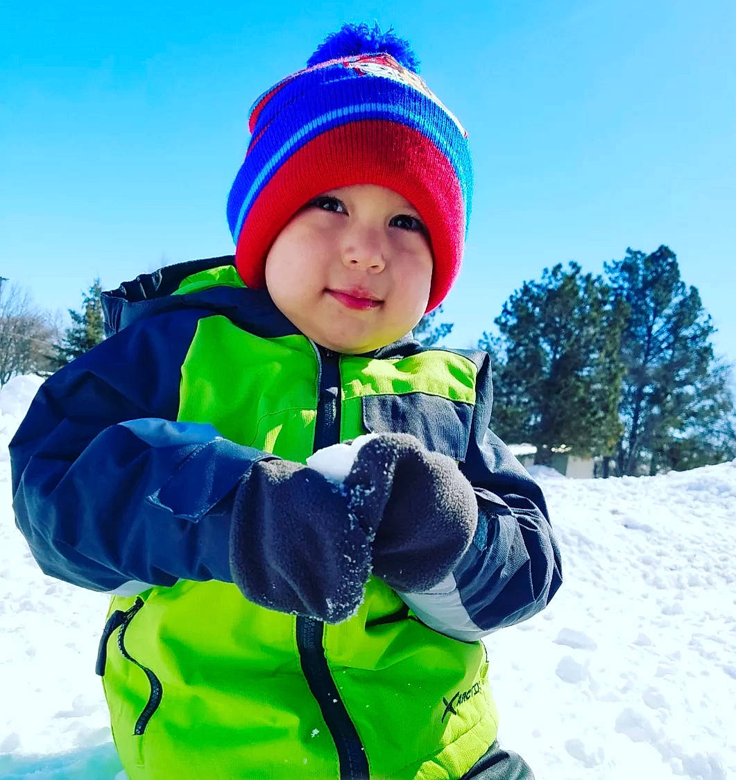 Liem is registered to the contest to win money with this photo: baby_toddler_clothing, cap, electric_blue, freezing, fun, glove, happy, headgear, headwear, jacket, knit_cap, outerwear, person, plant, recreation, sky, sleeve, slope, smile, snow