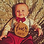 baby, infant, four_months, smiling, bow_tie, suspenders, red_clothing, wooden_sign, patterned_blanket, cute, portrait, lying_down, happy, child, face, hand, clothing, indoor, person, closeup