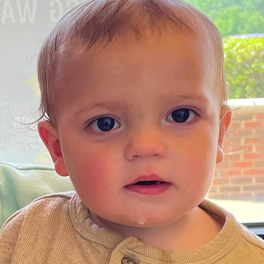 Jamarii is registered to the contest to win money with this photo: toddler, child, face, blue_eyes, drool, beige_shirt, closeup, indoor, window, curly_hair, young_child, portrait, skin, person, baby, expression, cute, casual_clothing, daylight, natural_light