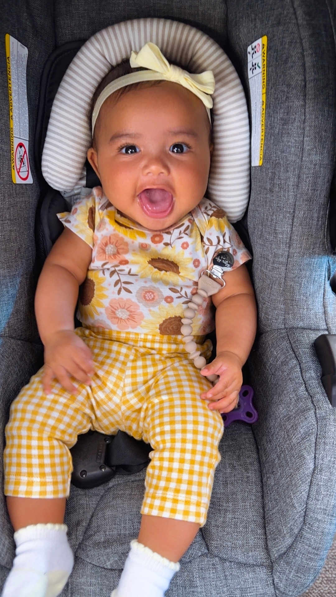 Kensie is registered to the contest to win money with this photo: baby, child, smiling, happy, car_seat, headband, yellow_pants, floral_top, socks, infant, cute, indoors, seat_belt, clothing, person, portrait, young_child, baby_accessory, fabric, seat