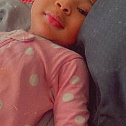 Ariana joined the competition — help win amazing prizes! child, baby, pink_clothing, polka_dots, pillow, lying_down, face, portrait, resting, indoor, cozy, young_child, soft_expression, bed, blanket, head, close_up, casual, sleepwear, relaxed