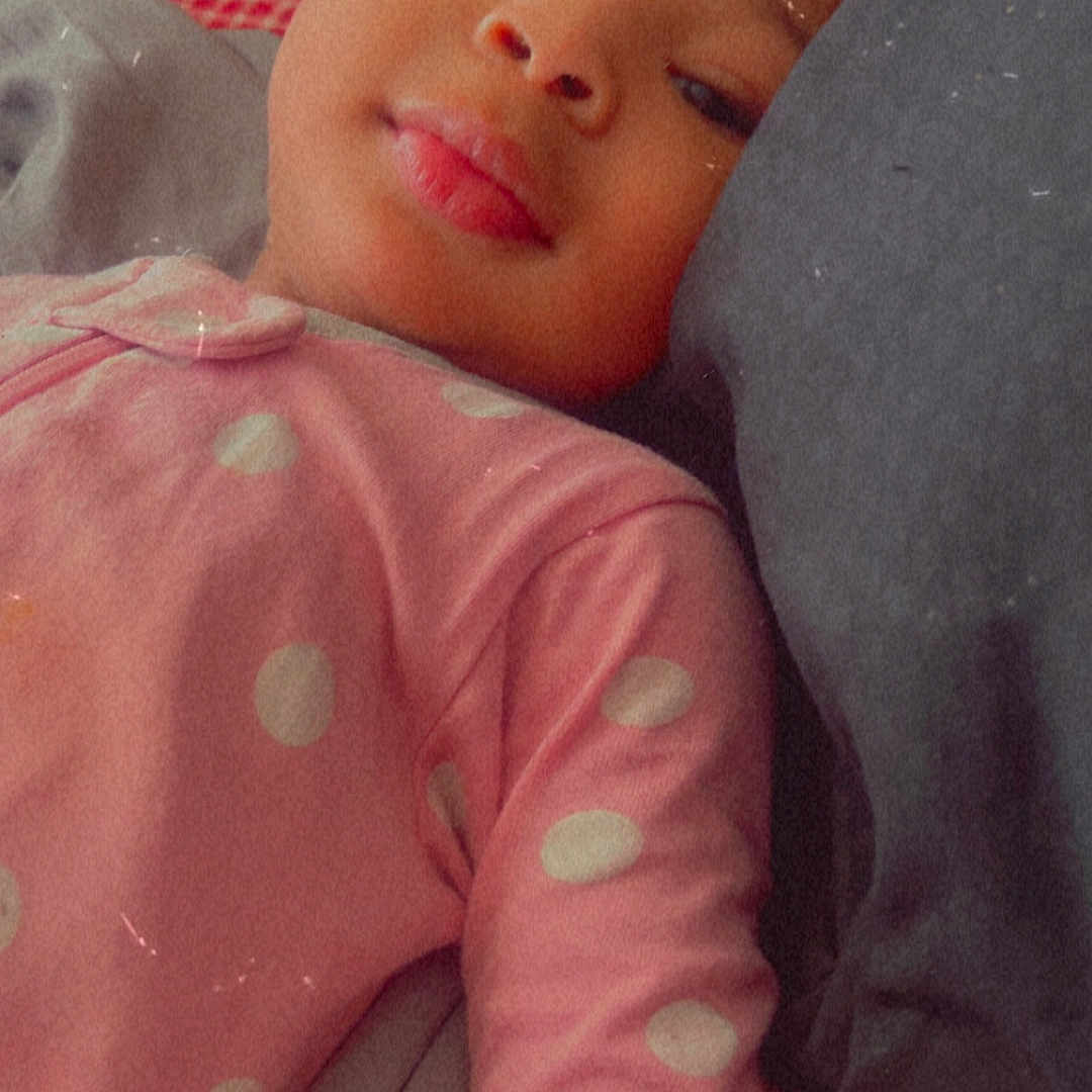 Ariana joined the competition — help win amazing prizes! child, baby, pink_clothing, polka_dots, pillow, lying_down, face, portrait, resting, indoor, cozy, young_child, soft_expression, bed, blanket, head, close_up, casual, sleepwear, relaxed