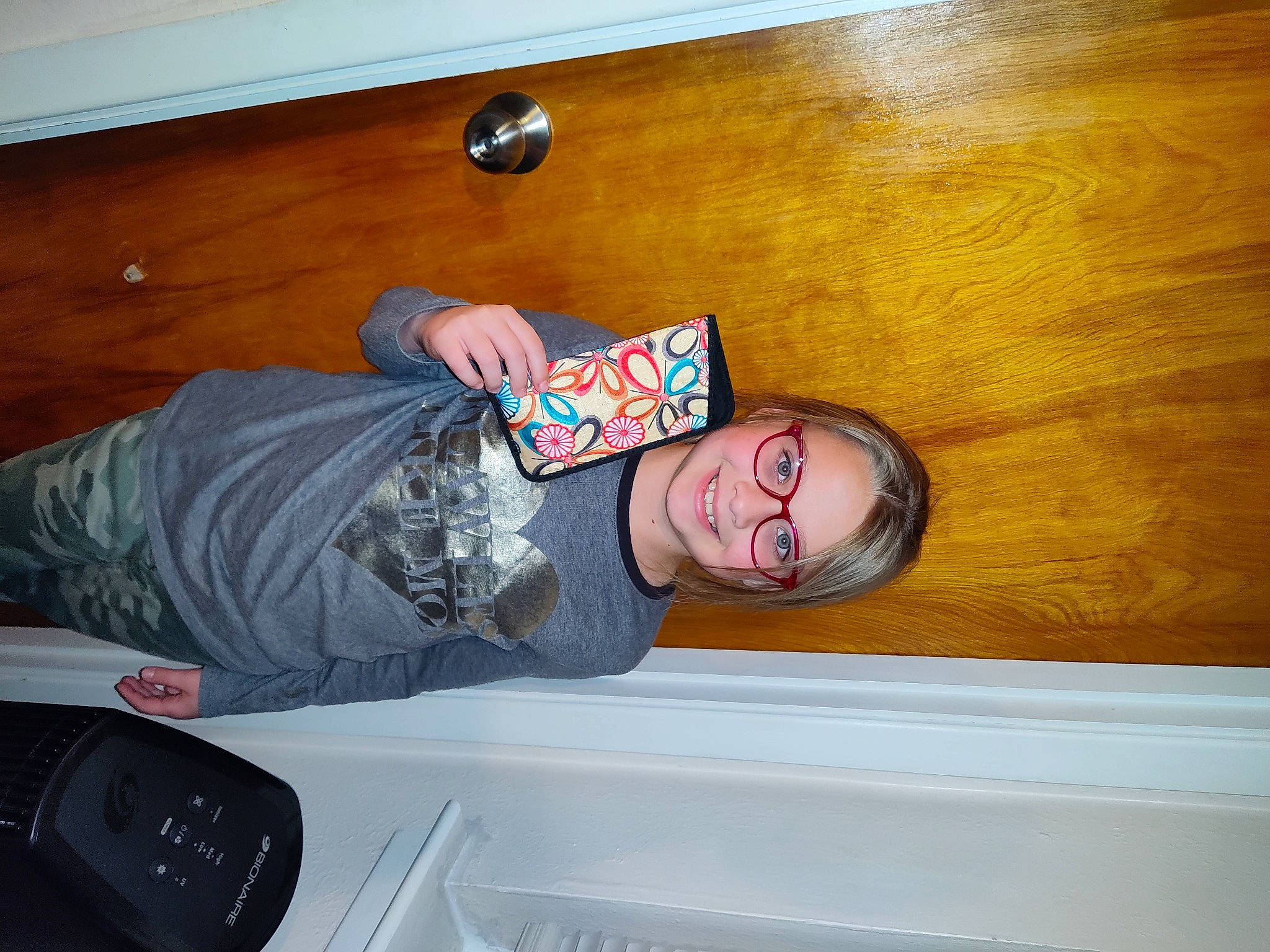 Lacie is registered to the contest to win money with this photo: comfort, cool, elbow, eyewear, flooring, fun, happy, hardwood, human_leg, joy, knee, mobile_phone, person, room, sitting, smile, t_shirt, thigh, varnish, wood