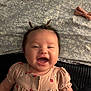 baby, smiling, infant, cute, pigtails, happy, child, face, pink_dress, patterned_blanket, bow, lying_down, indoors, portrait, young_child, joyful, skin, person, baby_clothes, toddler