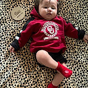 Kaia is registered to the contest to win money with this photo: baby, infant, red_bow, red_hoodie, red_socks, leopard_print, blanket, wooden_plaque, five_months, face, child, person, cute, lying_down, clothing, indoor, portrait, baby_girl, milestone, casual