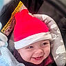 baby, smile, santa_hat, red_hat, car_seat, blanket, cozy, cute, child, infant, happy, face, clothing, seatbelt, headwear, indoors, portrait, holiday, expression, toddler