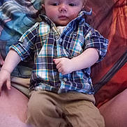 Valerian joined the competition — help win amazing prizes! baby, child, plaid_shirt, beige_pants, person, lap, indoor, bed, bedding, colorful, casual_clothing, portrait, young_child, relaxed, sitting, face, cute, infant, hands, legs