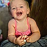 toddler, child, smiling, happy, pink_clothing, hands, face, indoor, wooden_background, person, cute, baby, portrait, expression, skin, hair, clothing, young_child, joy, sitting