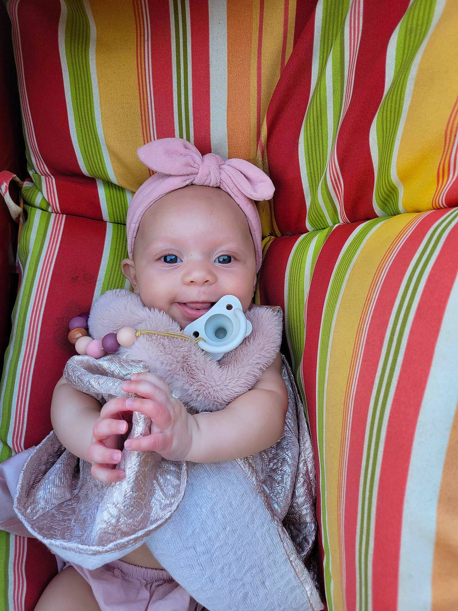 Katerina is registered to the contest to win money with this photo: baby, baby_carriage, baby_products, baby_toddler_clothing, chair, cheek, child, comfort, fashion_accessory, happy, head, linens, magenta, pattern, person, pink, room, sitting, smile, textile