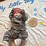 baby, infant, pacifier, blanket, onesie, gray_clothing, striped_clothing, wooden_plaque, text, stars, elephant, blue_text, yellow_stars, soft_texture, lying_down, raised_arm, footwear, newborn, three_months, cute