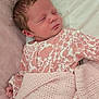 newborn, baby, sleeping, blanket, pink, floral_pattern, onesie, pillow, bed, soft_texture, cute, infant, peaceful, rest, indoors, child, face, hand, cozy, portrait